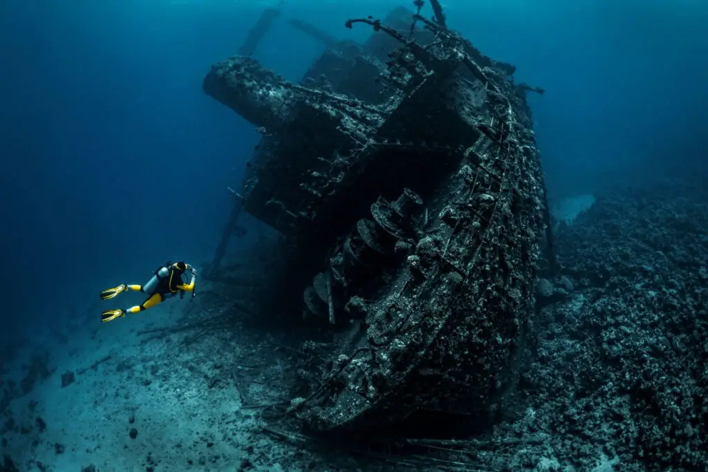 Scuba diver passing by a wreckage of a large sunken ship in the Red Sea. - Photo by Istock at Istock
